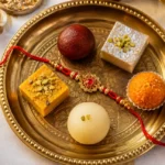 Traditional thali with regional rakhi sweets including pinni, ghevar and peda