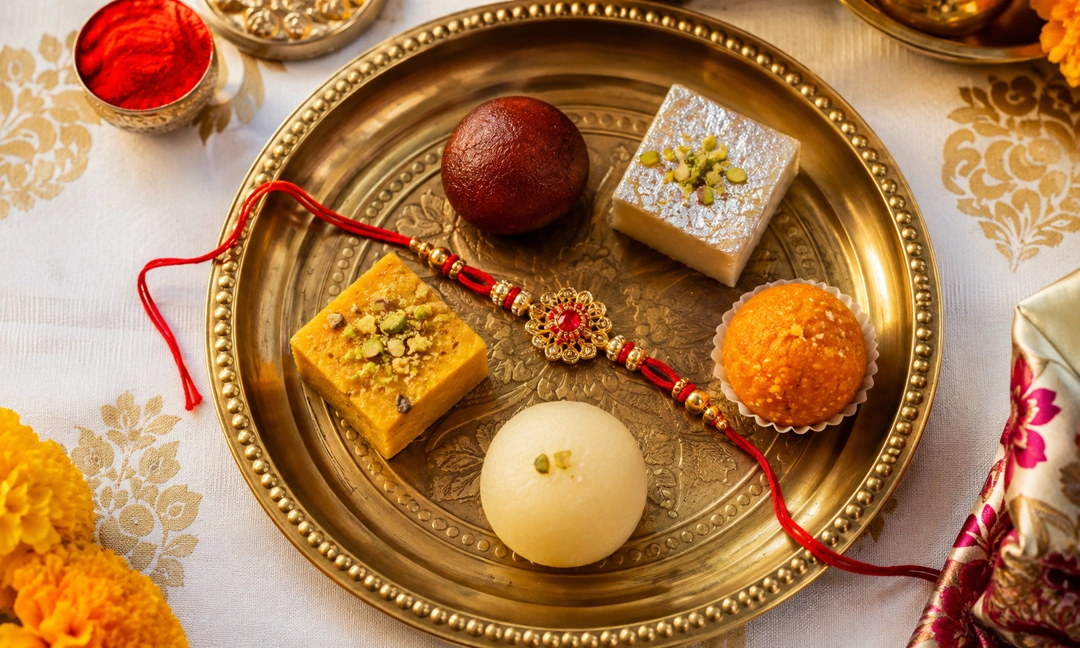 Traditional thali with regional rakhi sweets including pinni, ghevar and peda